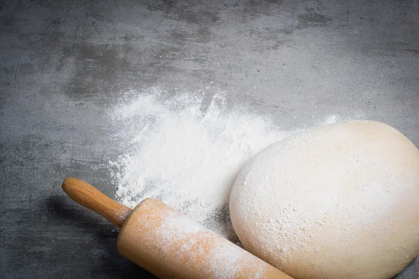 Dough, flour and rolling pin on a stone table — Stock Photo, Image