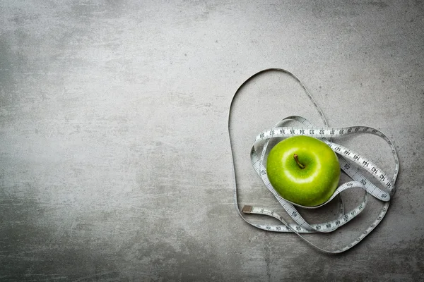 Ein grüner Apfel auf Betongrund mit Maßband — Stockfoto