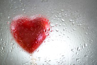 Islak bir pencere arkasında kırmızı kalp