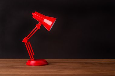 Ahşap bir masa üzerine kırmızı metal lamba