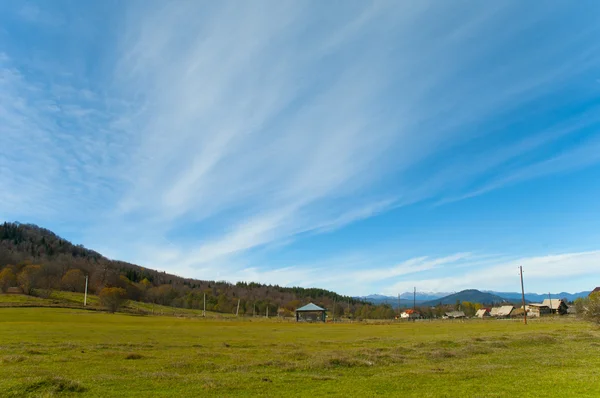 Groene weide en Blue Shiny Cloudscape en oude dorpswoningen in Bakoerjani Stockfoto