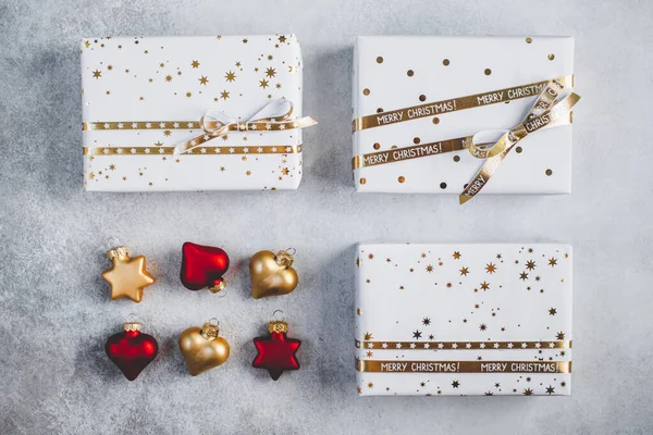 Coffrets cadeaux en papier blanc avec étoiles et points avec rubans dorés sur fond gris. Pose plate avec espace de copie. Image En Vente