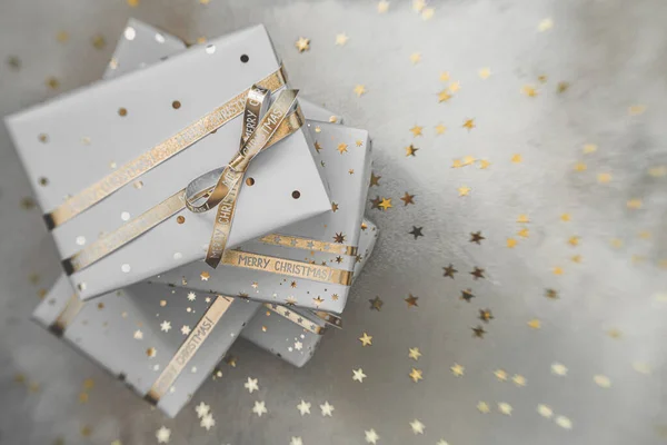 Подарункові коробки в білому папері з зірками і крапками з золотими стрічками на сірому фоні. Плоский простір для копіювання . — стокове фото