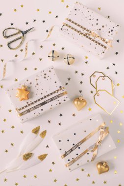 Beyaz kağıtta hediye kutuları içinde yıldızlar ve beyaz arkaplanda altın kurdeleler var.. 