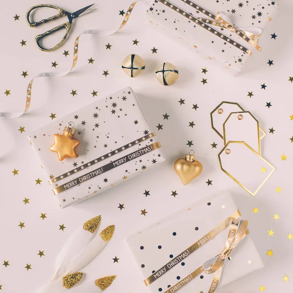 Подарункові коробки в білому папері з зірками і крапками з золотими стрічками на білому тлі . — стокове фото