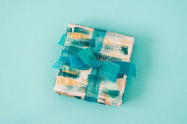 Geschenkdoos met smaragdgroene strik op een turquoise achtergrond. — Stockfoto