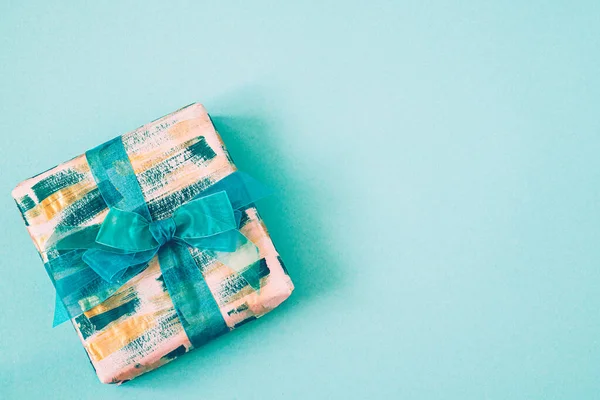 Geschenkdoos met smaragdgroene strik op een turquoise achtergrond met kopieerruimte. — Stockfoto