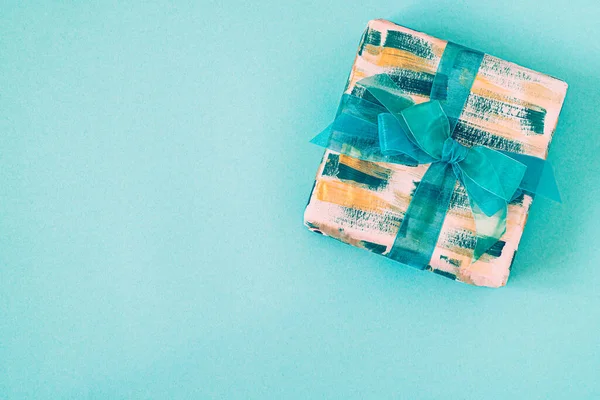 Geschenkdoos met smaragdgroene strik op een turquoise achtergrond met kopieerruimte. — Stockfoto