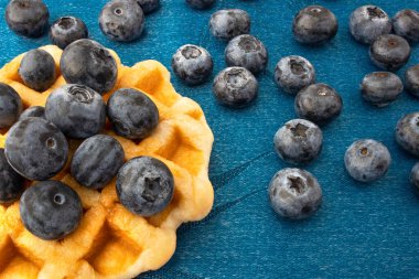 Waffle ve mavi ipek kumaş üzerine taze mavi böğürtlen, yakın çekim.