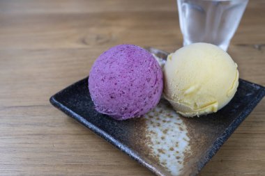 İki kepçe ev yapımı dondurma, biri Syzygium ağacının tropikal meyvelerinden veya mor renkli makiang ve diğeri de krem sarısı vanilyalı..