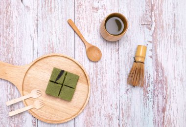 Bir porsiyon kibrit yeşil çay kenevirli kek ve yeşil çay, ahşap tabakta..