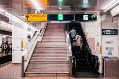 30 Mayıs 2013 Nagoya, Japonya - Meitetsu Nagoya İstasyonu 'nun yürüyen merdiveni ve merdivenlerindeki yolcular ve yön bilgisi ışık kutusu tabelası yukarıda asılı - Vintage film tarzı resim