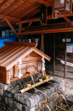 29 Mayıs 2013 Nagano, Japonya - Japonya 'nın Nakasendo antik ticaret yolu Narai-Juku Edo dönemindeki küçük bir türbede bambu kepçeli eski mahsul ahşap ahşap kaynak suyu pavyonu