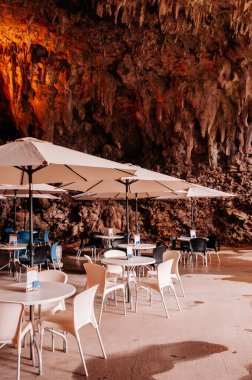 28 Ocak 2013 Naha, Okinawa, JAPAN: Oxotic Okinawa World Bunka Okoku Gyokusendo, Gangala Vadisi 'ndeki mağara kafe masaları ve şemsiyeler