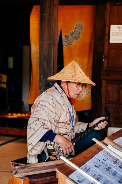 28 Ocak 2013 Naha, Okinawa, JAPAN: Geleneksel giysili ve şapkalı yaşlı adam Sanshin Okinawa - Japon geleneksel klasik müzik enstrümanı