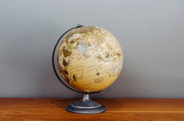 Dünya 'nın klasik okul modeliydi. Küre ikonu. Dünya üzerindeki kıtaların ve okyanusların küresel haritası. Doğal ahşap zemin zeminindeki gri zemin modeli.