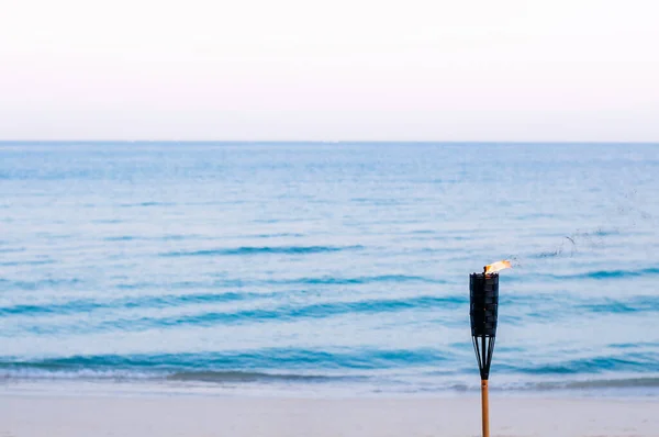 Bamboo fire torch on sunset tropical beach - Peaceful evening Thailand summer beach background concept