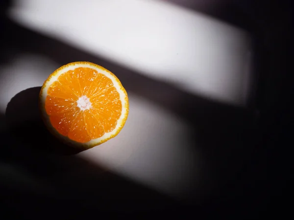 Yarı yarıya Mandarin portakalı güzel posası akşam ışığı ve gölge altında yerde.