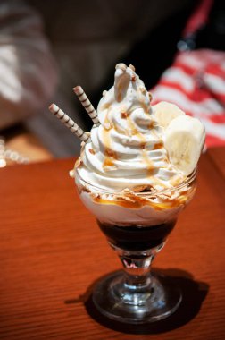 Vanilyalı dondurmayı gofretli, muzu cam bardakta ahşap masada yakın plan çek.