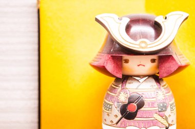 Japon tahta bebeği Kokeshi, Samuray Kokeshi sarı arka planda.