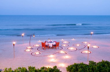 Tayland 'da akşam vakti, adanın sahilindeki balayı yemek masasında mumla.