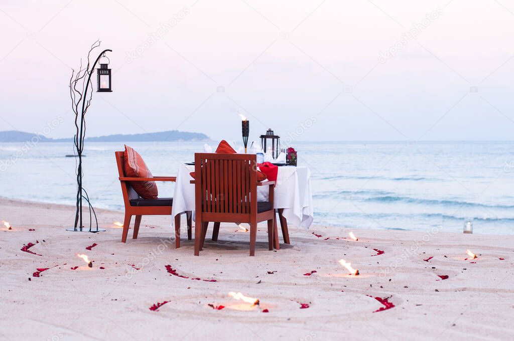Honeymoon dinner table on island beach with candle at evening in Thailand