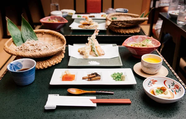 Tempura Zaru soğuk soba seti, tofu, Gobo kökü, sos ve wasabi seramik tabakta ve siyah masada.