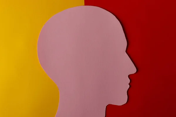 紙で作られたヘッドシルエット 黄色と濃い赤色の紙の背景にコピースペースを持つ人間の頭として形をしたピンクの紙 ミニマルなコンセプト — ストック写真