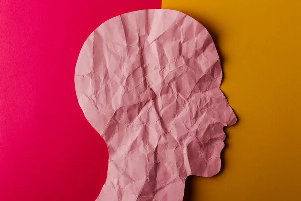 紙で作られたヘッドシルエット ピンクと黄色の紙の背景にコピースペースを持つ人間の頭として形をした砕いたピンクの紙 ミニマルなコンセプト — ストック写真