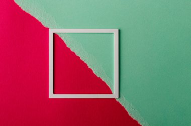 Pembe ve yeşil kağıtta fotokopi alanı olan beyaz plastik çerçeve. Yırtılmış kağıt. Asgari konsept.