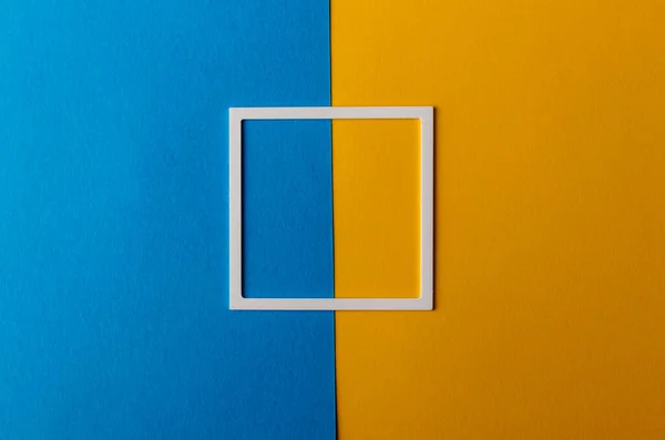 蓝色和黄色纸背景上有复制空间的白色塑料框架 最低限度概念 — 图库照片