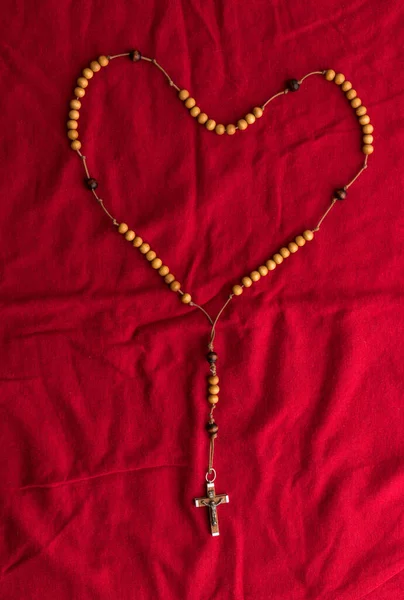 Rosary beads on red background. Christianity symbol with copy space.