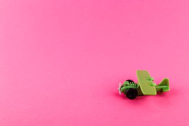 Pembe arka planda fotokopi alanı olan küçük plastik bir uçak. Oyuncak.