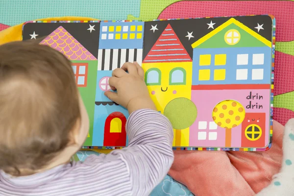 Младенец играет с красочной книгой — стоковое фото