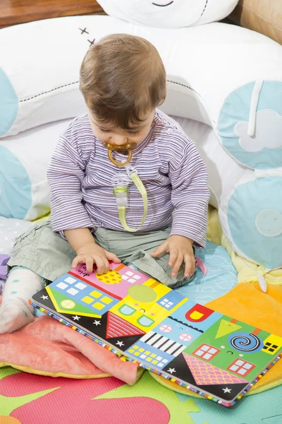 Barnet tittar ner på färgglada bok med bilder — Stockfoto