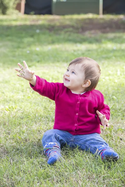 Härlig tjej med gräs i handen tittar upp och ler — Stockfoto