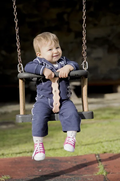 Porträtt av glada lilla bebis på svingen — Stockfoto
