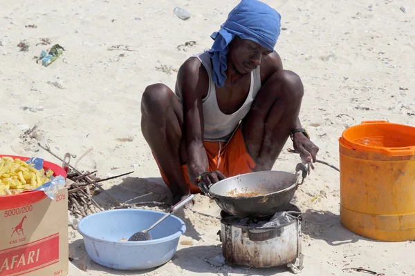 Hombre cocinando en la playa con una cocina sencilla improvisada — Foto de Stock