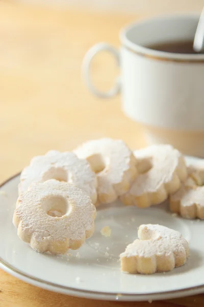 Galletas italianas mordidas de Canestrelli cerca de una taza de té negro —  Fotos de Stock