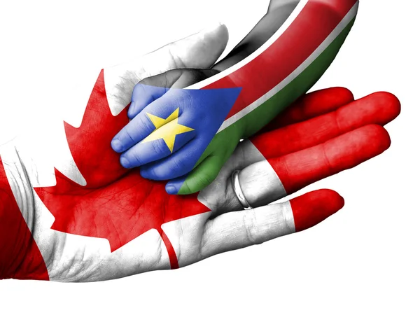 Volwassen mens bezit is van de hand van een baby met Canada en Zuid-Soedan vlaggen bedekt. Geïsoleerd op wit — Stockfoto