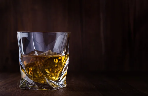 Glass of scotch whiskey and ice on a wooden background with copyspace — Stock Photo, Image
