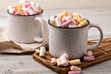 Tahta arka planda bir fincanda kremalı sıcak çikolata.