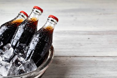 Ahşap bir masada buz yatağında soda şişesi. 