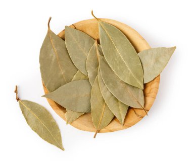 Kuru körfez yaprakları beyaz arka plandaki ahşap bir kasede, yukarıdan görülüyor.