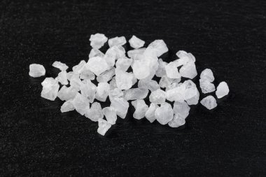 Kaba deniz tuzu kristalleri koyu bir arka planda.