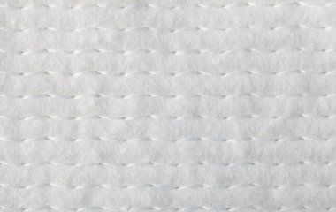 Beyaz yumuşak kumaş, örtülü dokuyu paralel dikişlerle gösteriyor.