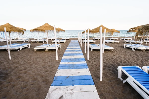 Vacker strand med solstolar och parasoller mot himmelsblå — Stockfoto