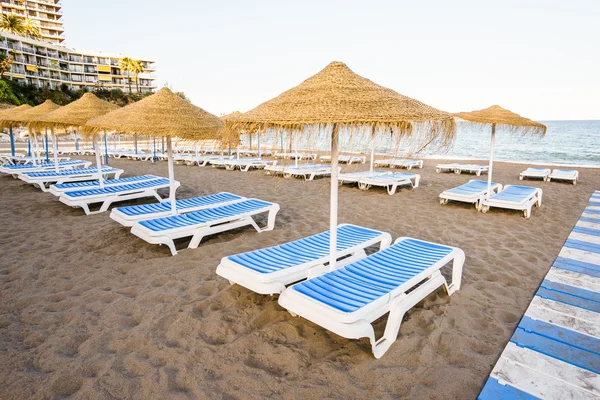 Bella spiaggia con sdraio e ombrelloni contro di cielo azzurro — Foto Stock