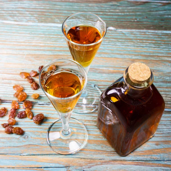 Close-up of glasses of cognac, bottle and raisin — Stock Photo, Image