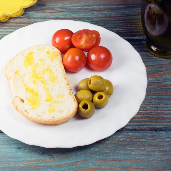 Detail z lahví olivového oleje, krajíc chleba, zelené olivy — Stock fotografie